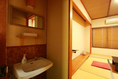 a bathroom with a sink and a mirror at Family Ryokan Kawakyu with Showa Retro, private hot spring in Ibusuki