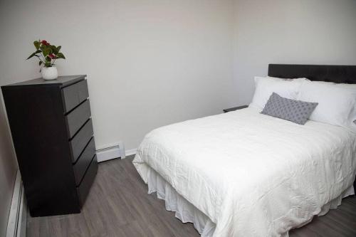 a bedroom with a white bed and a black dresser at Tranquil Retreats on Robinson in Moncton