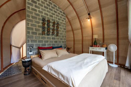a bedroom with a bed and a brick wall at Tớ Dày Du Già Village in Làng Cac