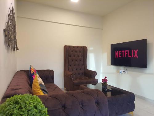 uma sala de estar com um sofá e uma televisão em OSI Apartments Santacruz em Mumbai