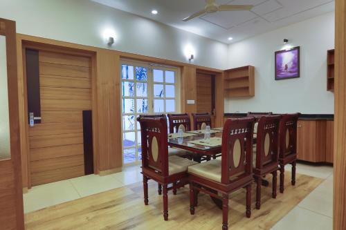 a dining room with a table and wooden chairs at Choice Beach House in Kannur