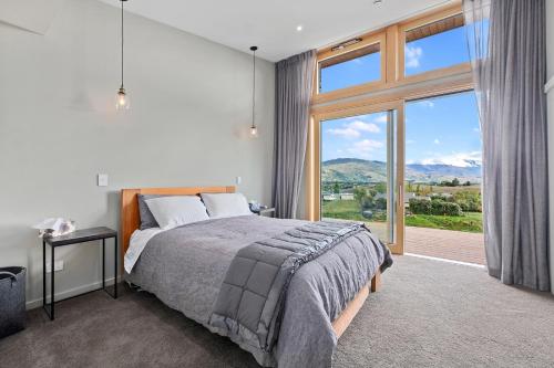 a bedroom with a bed and a large window at Vino and Views - Bannockburn Holiday Home in Cromwell