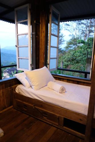 uma cama num quarto com duas janelas em Camp-Ula em Sampalok