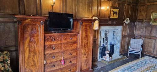 een houten dressoir met een televisie erop bij Braithwaite Hall Bed & Breakfast in Middleham