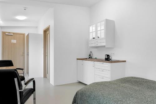 a white room with a bed and a kitchen at Klettar - The Old Hatchery Iceland in Fludir