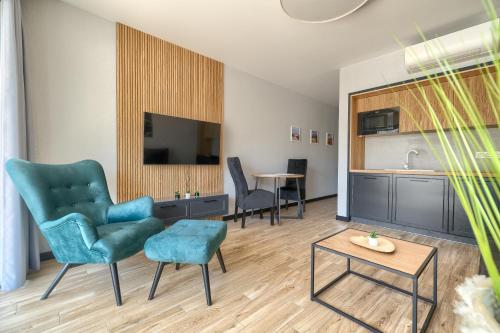 a living room with chairs and a tv and a table at Apartamenty Solaris in Darłówko