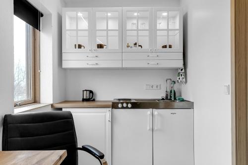 a kitchen with white cabinets and a sink and a table at Klettar - The Old Hatchery Iceland in Fludir