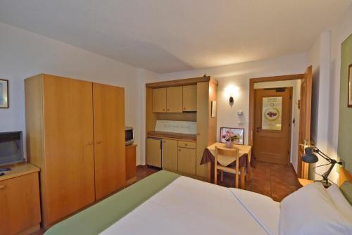 a bedroom with a bed and a kitchen with a table at La Roche Hotel Appartments in Aosta