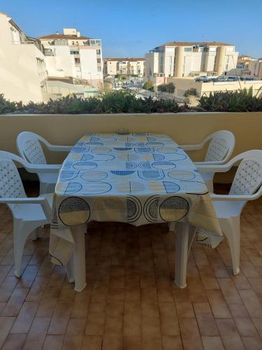 une table avec des chaises autour sur un balcon dans l'établissement T2 4 pers, rénové en bord de plage , clim et parking classé 2 étoiles, à Sète