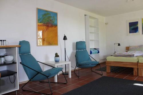 sala de estar con 2 sillas azules y mesa en Gemütliche Wohnung mit Terrasse in der Nähe vom Bodensee, en Tettnang