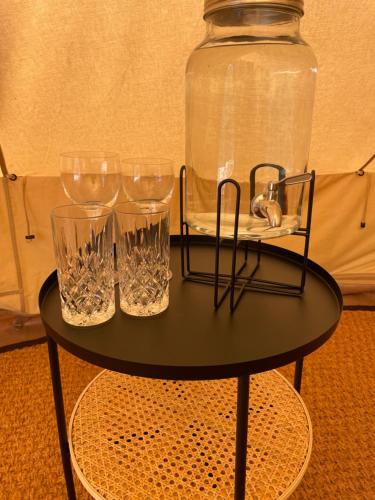 a black table with glasses and a large jar on it at Glamping Tält Mariehamn in Mariehamn