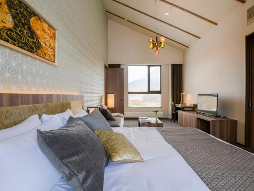 a bedroom with a large white bed and a television at Panorama Niseko in Kutchan