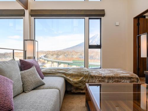 a living room with a couch and a large window at Panorama Niseko in Kutchan