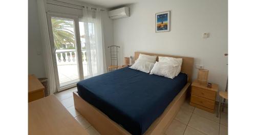 una camera da letto con un letto con lenzuola blu e una finestra di Cap Ras a Empuriabrava