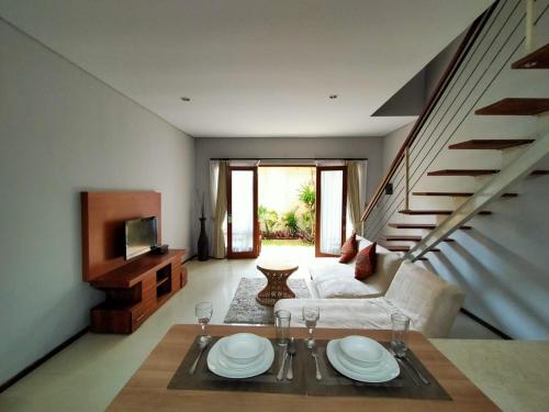 a living room with a table and a couch and stairs at Balcony Living Apartment in Seminyak