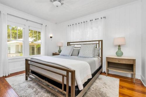 a white bedroom with a bed and two windows at Cabin Style Pool Home w/ Guesthouse! Sleeps 10! in Stuart