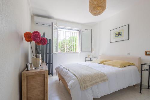 ein weißes Schlafzimmer mit einem Bett und einem Fenster in der Unterkunft U Momentu - appt climatisé avec terrasse in LʼÎle-Rousse