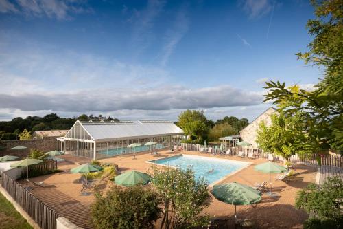 une piscine avec des parasols et un bâtiment dans l'établissement Huttopia Saumur, à Saumur