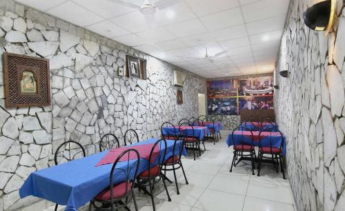 a dining room with blue tables and chairs and a stone wall at Hotel O Rajmahal in Jalandhar