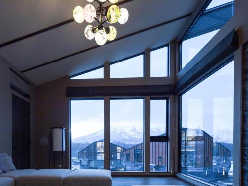 a living room with large windows and a chandelier at Panorama Niseko in Kutchan