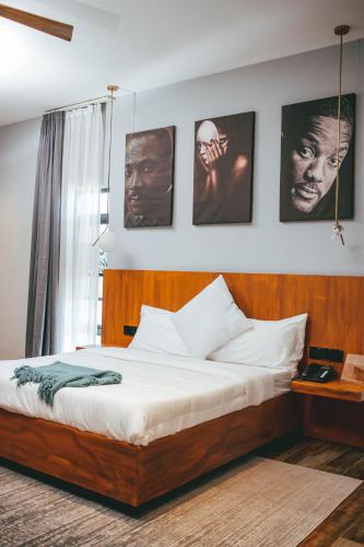 a bed in a bedroom with pictures on the wall at Burundi Palace Boutique Hotel in Bujumbura