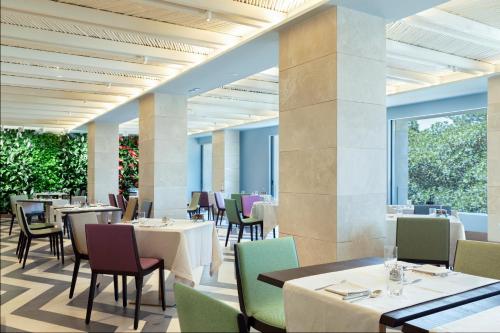 a dining room with tables and chairs and windows at Grand Hotel Des Etrangers in Siracusa