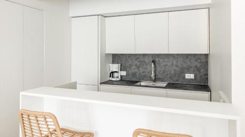 een keuken met witte kasten, een wastafel en 2 stoelen bij Italyescapes Emma 22 NEW 2023 in Merano