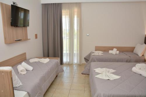 a hotel room with two beds with towels on them at Denis Hotel and Bungalows in Korinós