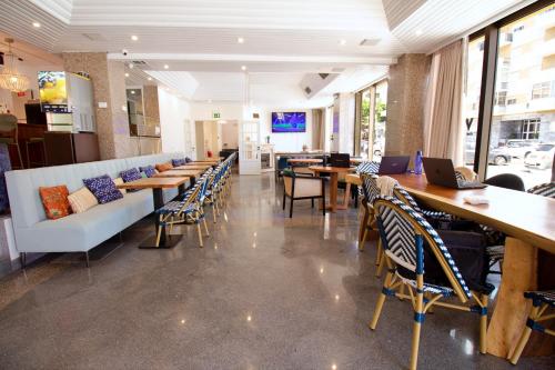 ein Restaurant mit Tischen und Stühlen mit Laptops darauf in der Unterkunft WOT Costa da Caparica in Costa da Caparica