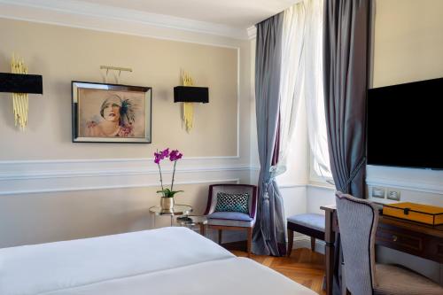 a bedroom with a bed and a desk and a tv at Grand Hotel Des Etrangers in Siracusa