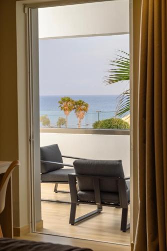 a room with a view of the ocean through a sliding glass door at Nicolas Grand Suites, Adults Only in Kardamaina