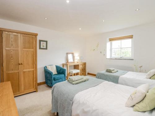 a bedroom with two beds and a blue chair at Shundraw Cottage in Keswick