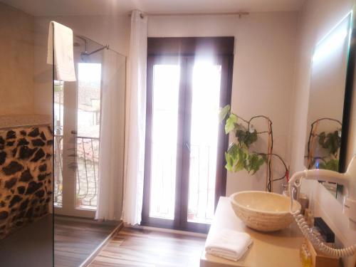 a bathroom with a sink and a glass door at Escapada Romantica con Jacuzzi y vistas al Castillo de Trevejo in Villamiel