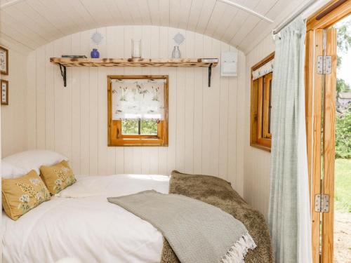シャルドンにあるCoombe Valley Shepherd's Hutの窓付きの小さな部屋のベッド1台分です。