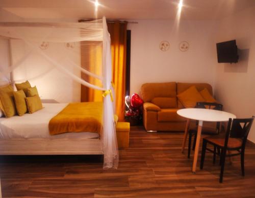 a bedroom with a bed and a table and a couch at Habitación ideada para parejas con Jacuzzi, desayuno romántico y opción de cenas en su restaurante in Villamiel