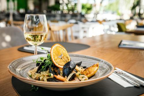 a plate of pasta with an orange slice and a glass of wine at Hotel Trotuş in Onești