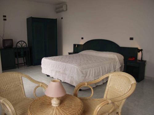 a bedroom with a bed and two chairs and a table at Hotel Ristorante La Scogliera in Amantea
