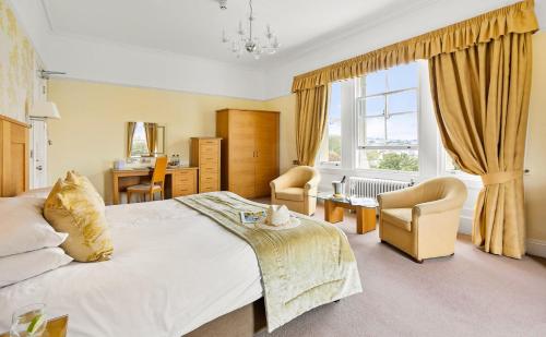 a bedroom with a bed and chairs and a window at The Falmouth Hotel in Falmouth