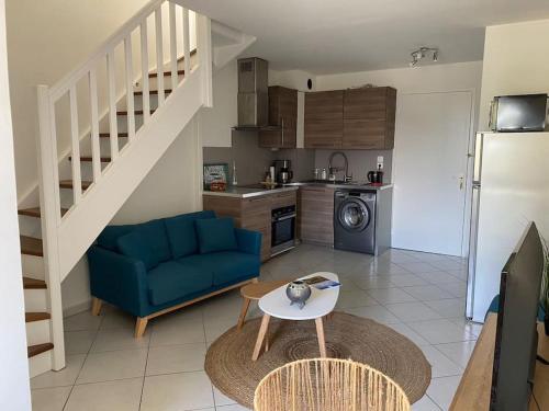 un salon avec un canapé bleu et une cuisine dans l'établissement Ravissant T3 en duplex proche mer, à La Londe-les-Maures
