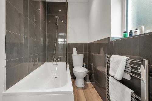 a bathroom with a white tub and a toilet at Modern Apartment in South West Wandsworth in London