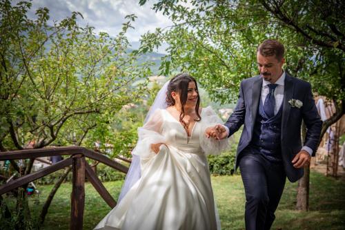 a bride and groom walking down a bridge at Borgo Casale in Albareto