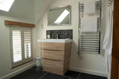 W łazience znajduje się umywalka i lustro. w obiekcie The Piggery w mieście Cowfold