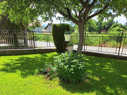 une clôture dans une cour avec un arbre et un bush dans l'établissement Apartman Ivo, à Livno