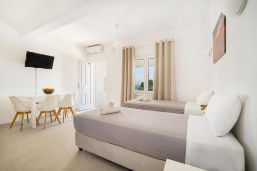 a bedroom with two beds and a table and chairs at Oniropetra Apartments Mykonos in Plintri