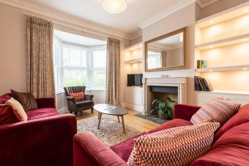 a living room with a red couch and a fireplace at Norfolk House - Stamford in Stamford
