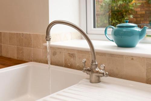 a kitchen sink with a water faucet and a vase at Norfolk House - Stamford in Stamford