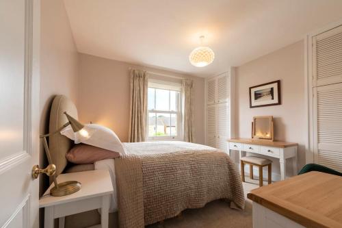 a bedroom with a bed and a desk and a window at Norfolk House - Stamford in Stamford
