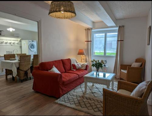 a living room with a red couch and a table at La Métairie de la Pétillerie in Roullet-Saint-Estèphe