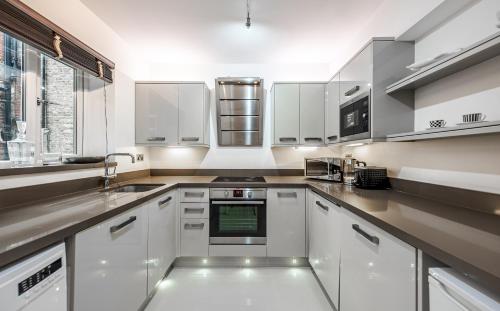 a kitchen with white cabinets and a stove top oven at Flat 8 in London