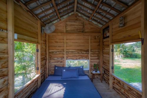 a bed in a log cabin with two windows at Homie Hava Homestay in Lang Co